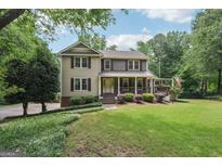 Charming two-story home with a welcoming front porch and a well-manicured lawn at 10875 Shagbark Trl, Roswell, GA 30075