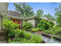 Charming home featuring a well-maintained yard with lush landscaping and a brick entryway at 1977 Kensington High Sw St, Lilburn, GA 30047