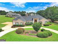 Beautiful single-story home with a circular driveway, manicured lawn and lush landscaping at 335 Canvasback Trl, Locust Grove, GA 30248