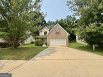 Traditional brick-accented home featuring an attached two-car garage and a well-manicured front lawn at 105 Avonwood Cir, Locust Grove, GA 30248