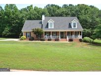 Charming brick home with a lush green lawn and inviting front porch nestled among mature trees at 500 Hayfield Ct, Locust Grove, GA 30248