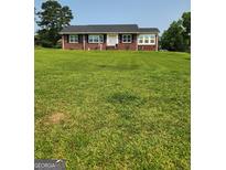 Charming one-story brick home with a neatly mowed front yard and a classic white door at 619 E College St, Bowdon, GA 30108