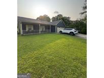 Charming single-story home with well-manicured lawn, front porch, and attached garage on a sunny day at 6403 Heritage Run, Morrow, GA 30260