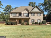 Traditional brick home with a manicured lawn, inviting curb appeal and a symmetrical facade at 137 Nobility Ln, Mcdonough, GA 30252