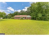 Charming brick home featuring a spacious front yard with mature trees and a well-maintained lawn at 195 Southmoor Cir, Stockbridge, GA 30281