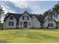 Charming two-story home with a landscaped yard and classic brick facade under a cloudy sky at 100 Regina Ct, Fayetteville, GA 30215