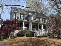 Charming two-story home boasts a large porch with white columns, beautiful landscaping, and mature trees at 107 Terrane Rdg, Peachtree City, GA 30269