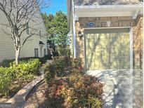 View of the exterior brick and siding of townhome at 2540, featuring a one-car garage and manicured front garden at 2540 Willow Grove Road Nw Rd # 15, Acworth, GA 30101