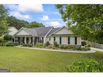 Charming single story home with manicured lawn, mature trees, and colorful flowerbeds adding curb appeal at 301 Bradford Ct, Auburn, GA 30011