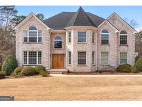 Stately two-story brick home with arched windows, mature landscaping, and a manicured front lawn at 1202 Persimmon Way, Mcdonough, GA 30252