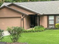 Charming single-story home featuring a front yard, attached garage, and covered porch perfect for relaxing at 6884 Shangrila Way, Riverdale, GA 30296