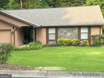 Charming single-story home with stone accents, well-maintained lawn, and lush landscaping at 6884 Shangrila Way, Riverdale, GA 30296