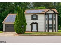 Inviting two-story home featuring solar panels, a garage, and neatly manicured landscaping at 3255 Hunters Crossing Pt, Lithonia, GA 30038