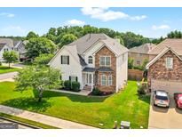Charming two-story home featuring stone accents, well-maintained landscaping, and a lush green lawn at 910 Pebble Creek Trl, Suwanee, GA 30024