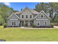 Charming two-story home featuring a stone facade, gray siding, well-manicured lawn, and welcoming front porch at 33 Vinery Ct, Sharpsburg, GA 30277
