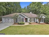 Charming single-story home with a well-manicured lawn, attached two-car garage and lush green trees surrounding the property at 505 Bracken Edge, Peachtree City, GA 30269
