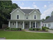 Charming two-story home featuring a welcoming front porch and manicured landscaping at 100 Rabbits Run, Fayetteville, GA 30214