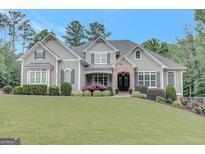 Stunning gray home featuring a stone entryway, manicured lawn, and lush landscaping at 265 Beverly Farms Dr, Sharpsburg, GA 30277