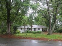 Charming one-story home with mature trees and a well-maintained lawn and white painted brick at 1726 Centra Villa Sw Dr, Atlanta, GA 30311