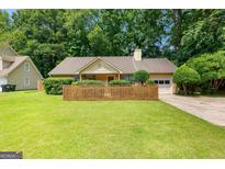 Charming one-story home featuring a wooden fence, attached garage, and lush green lawn at 110 Long Leaf, Peachtree City, GA 30269