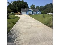 Charming blue ranch-style home with a long driveway and well-manicured lawn at 160 Springdale Ct, Newborn, GA 30056