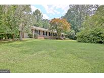 Charming brick ranch-style home with a well-manicured lawn and mature trees at 501 Bridlepath Ln, Peachtree City, GA 30269