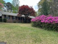 Charming brick home featuring a lush lawn, vibrant azalea bushes, and a beautiful Japanese maple tree at 501 Bridlepath Ln, Peachtree City, GA 30269