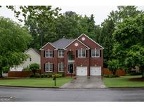 Stately brick home featuring a two-car garage and manicured front lawn at 8035 Magnolia Way, Roswell, GA 30075