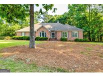 Charming brick home featuring well-maintained landscaping, arched window, and mature trees at 195 Youngs Cir, Fayetteville, GA 30215