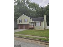Charming home featuring a two-car garage, green siding, and mature trees, perfect for suburban living at 35 Hampton Oaks Dr, Hampton, GA 30228