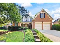 Charming brick home featuring a well-manicured lawn and two-car garage at 795 Lake Medlock, Alpharetta, GA 30022