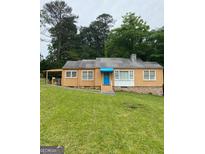 Charming single-story home featuring a quaint blue door and complemented by a well-maintained, expansive lawn at 5094 Covington Hwy, Decatur, GA 30035