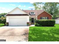 Charming single-Gathering home featuring a manicured lawn, brick accents and an attached two-car garage at 8180 Chapman Ter, Mcdonough, GA 30252