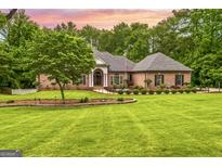 Stunning brick home with lush landscaping, mature trees, and a sprawling green lawn at 150 Old Plantation Way, Fayetteville, GA 30214