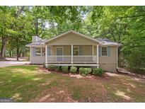 Charming home featuring a cozy front porch with white railings and blue shutters and door at 438 Punkintown Rd, Villa Rica, GA 30180