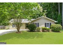 Charming single-story home featuring a well-manicured lawn and beautiful flowering trees at 409 Deergrass Trl, Peachtree City, GA 30269