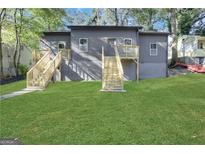 Gray home featuring a lush lawn and two sets of wooden stairs leading to elevated entrances at 1226 Byewood Sw Ln, Atlanta, GA 30310
