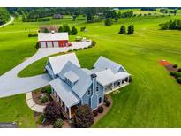 Stunning aerial view of modern farmhouse with pristine landscaping, metal roof, and a large red barn at 385 Liberty Church Rd, Carrollton, GA 30116