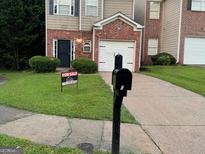 Traditional two-story home with brick and siding, featuring a one-car garage and well-maintained lawn at 5057 Windsor Forrest Lane, Atlanta, GA 30349