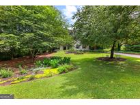 Charming home with a beautiful landscaped front yard and mature trees at 205 N Strathmore Dr, Sharpsburg, GA 30277