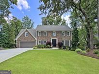 Charming brick two-story home with manicured lawn, beautiful landscaping, and a two-car garage at 335 S Satinwood Pl, Roswell, GA 30076