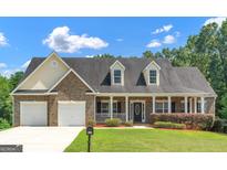 Charming brick home with a two-car garage, inviting front porch and lush landscaping at 185 Stewart Glen Dr, Covington, GA 30014