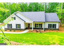 Inviting single-story home with a well-manicured lawn and charming curb appeal surrounded by a lush green forest at 5525 Belle Meade Dr, Villa Rica, GA 30180