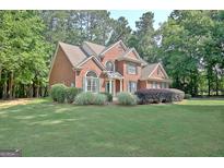 Beautiful brick home featuring a well-manicured lawn and lush landscaping at 185 Newfield Dr, Tyrone, GA 30290