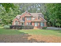 Charming two-story red brick home with lush green lawn and mature trees at 185 Newfield Dr, Tyrone, GA 30290