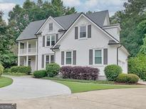 Elegant two-story home featuring a white facade, dark shutters, manicured landscaping, and a circular driveway at 505 Lighthouse Ln, Peachtree City, GA 30269