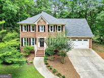Charming two-story brick home featuring a well-manicured lawn, mature trees, and an attached two-car garage at 135 Crimson Rdg, Tyrone, GA 30290