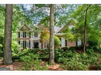 Traditional brick home featuring dark shutters, manicured landscaping and mature trees on a sunny day at 120 Oak Shadow Way, Fayetteville, GA 30215