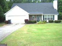 Charming single-Gathering home featuring stone accents, a well-manicured lawn, and an attached garage at 225 Long Creek Dr, Covington, GA 30016