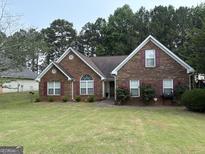 Charming brick home with well-manicured lawn, red shutters, and lush landscaping at 85 Bermuda Run Dr, Covington, GA 30016
